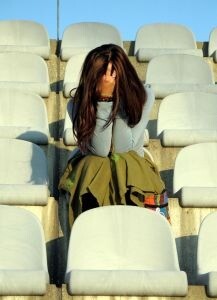 woman sitting alone feeling desperate in the bleachers